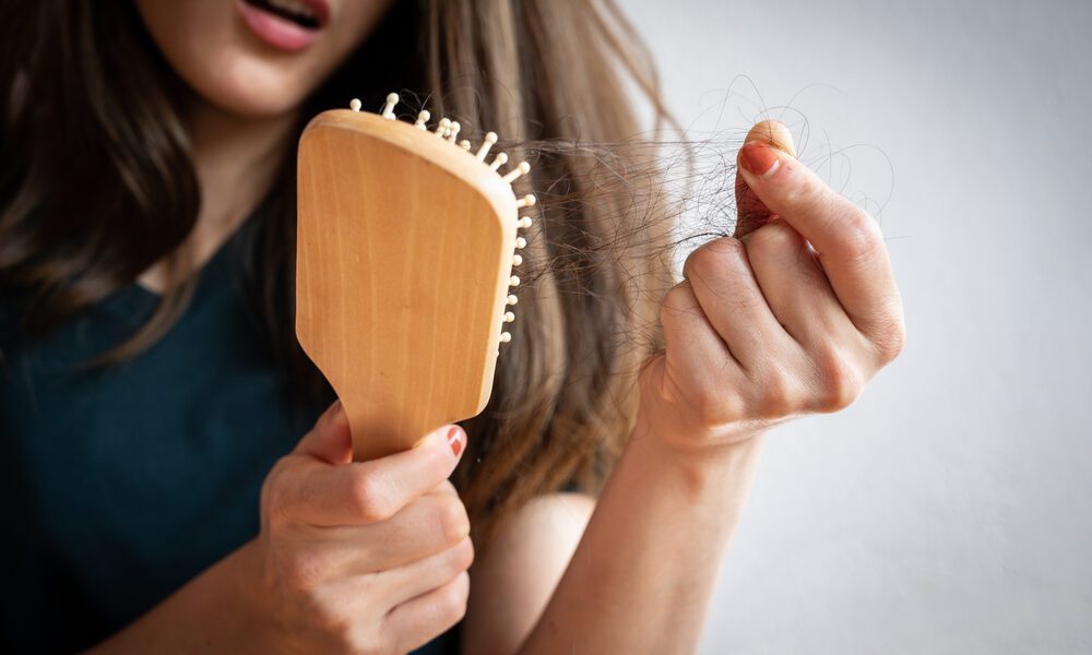 Mulher segura pente de cabelo e puxa fios