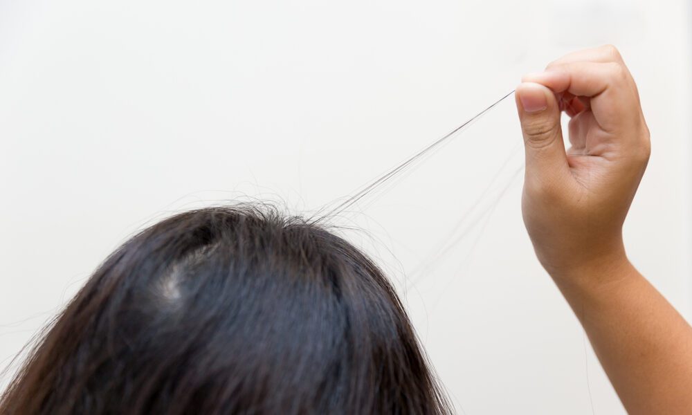 Mulher puxando fio de cabelo em fundo branco